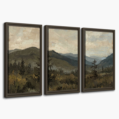 Layered mountain ridges and dark evergreen trees beneath a muted cloudy sky 3 piece framed canvas wall art on a white background