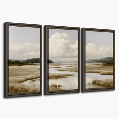 A pale winding waterway crossing quiet wetlands beneath billowing white clouds 3 piece framed canvas wall art on a white background