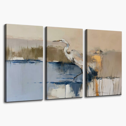 A slender heron standing in blue water among loose ochre and cream brushstrokes 3 piece canvas wall art on a white background