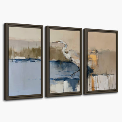 A slender heron standing in blue water among loose ochre and cream brushstrokes 3 piece framed canvas wall art on a white background