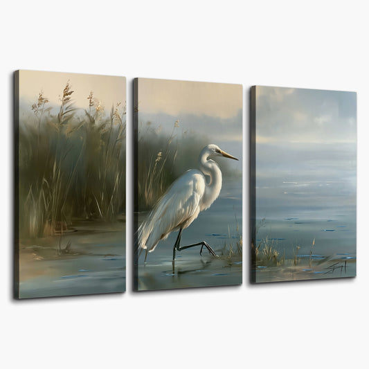 A white heron beside tall marsh grasses and still blue water 3 piece canvas wall art on a white background