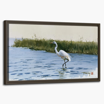 A white heron wading through bright blue water beside green reeds single framed canvas wall art on a white background