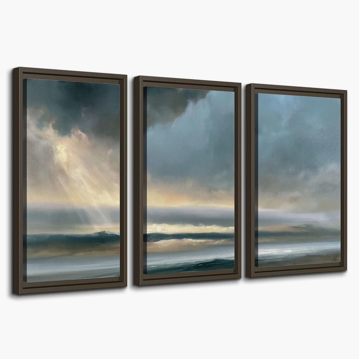 Dramatic blue-gray storm clouds breaking over a pale strip of ocean light 3 piece framed canvas wall art on a white background