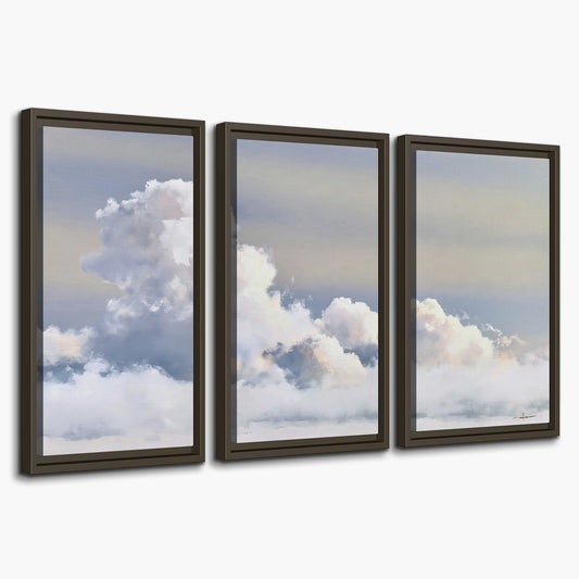 Large white clouds rising through a pale blue sky with gentle warm highlights 3 piece framed canvas wall art on a white background