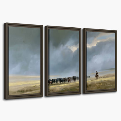 A rider and cattle moving across a sunlit grassland beneath a dramatic blue-gray sky 3 piece framed canvas wall art on a white background