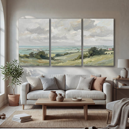 Coastal Countryside 3 piece canvas wall art set hanging in a bright living room with sofa and arched window