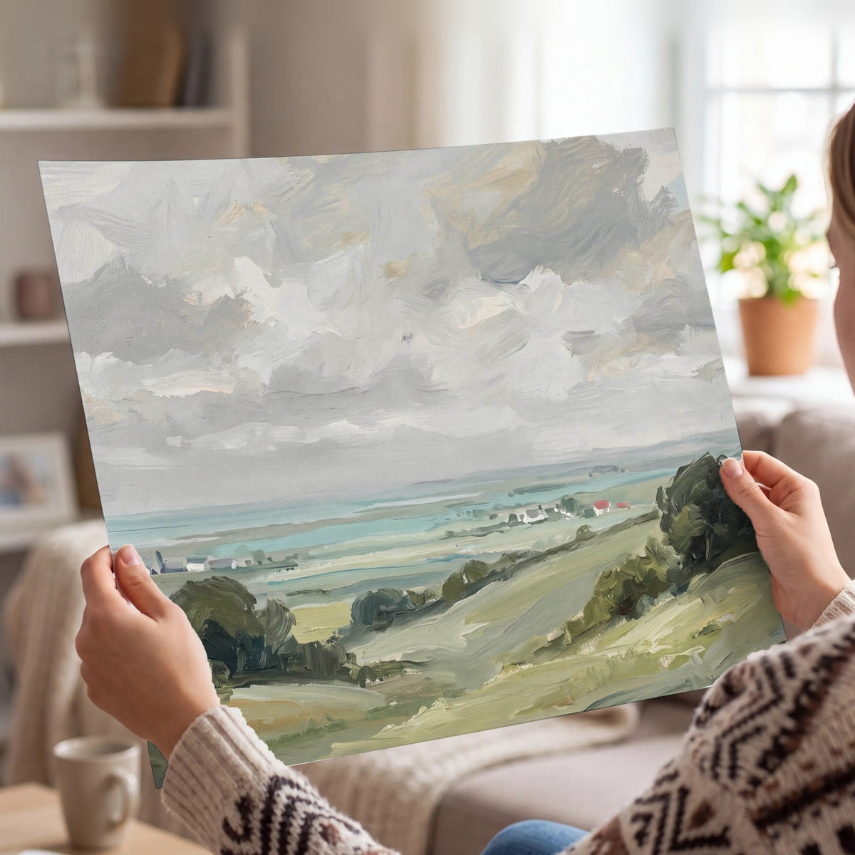 Woman holding a coastal countryside poster print on matte paper at home