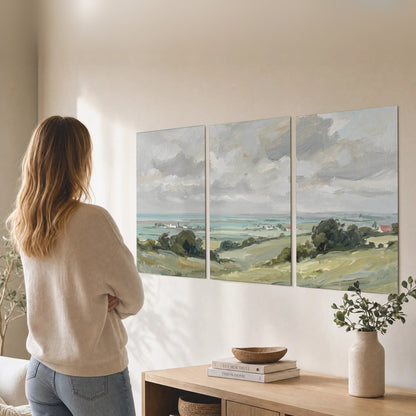 Set of 3 coastal countryside poster prints on a living room wall above a wooden console