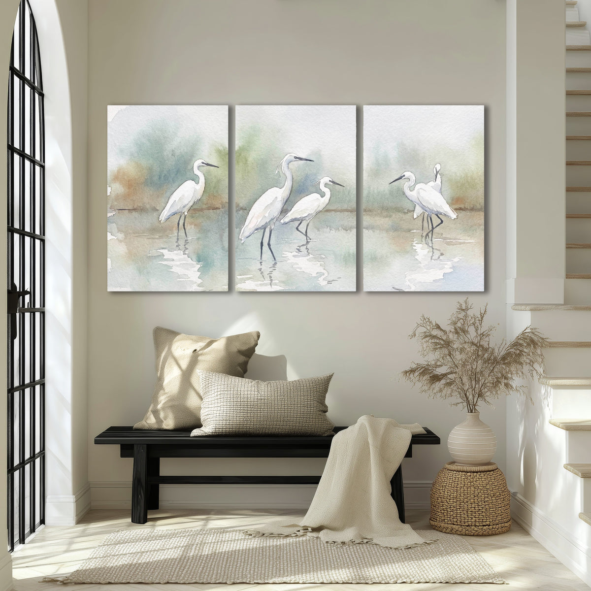 White egrets watercolor 3 piece canvas wall art in an entryway above a bench