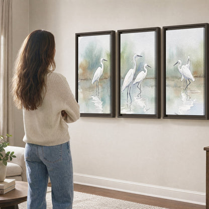 White egrets watercolor 3 piece framed canvas in a living room