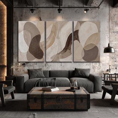 Layered organic shapes in taupe, cream and brown 3 piece canvas wall art displayed in a industrial room