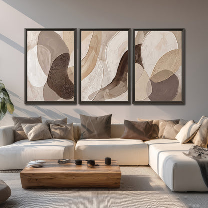 Layered organic shapes in taupe, cream and brown 3 piece framed canvas wall art displayed in a living room