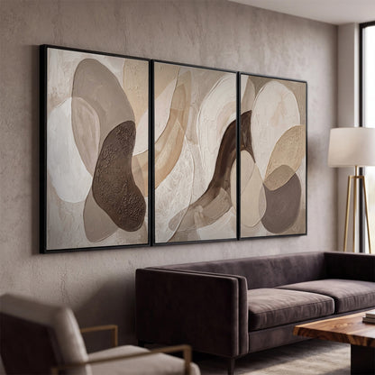 Layered organic shapes in taupe, cream and brown 3 piece framed canvas wall art displayed in a modern living room