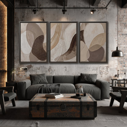 Layered organic shapes in taupe, cream and brown 3 piece framed canvas wall art displayed in a industrial room