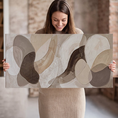 Layered organic shapes in taupe, cream and brown single canvas wall art held in hands