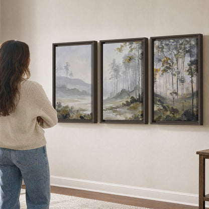Misty woodland stream with gray trees, muted olive foliage and distant hazy hills 3 piece framed canvas wall art three panel arrangement on a wall