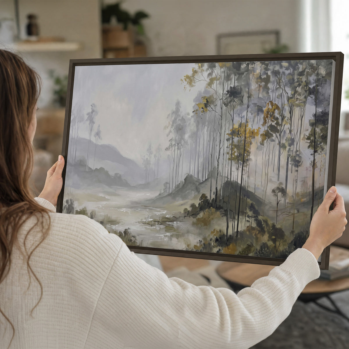 Misty woodland stream with gray trees, muted olive foliage and distant hazy hills single framed canvas wall art held in hands