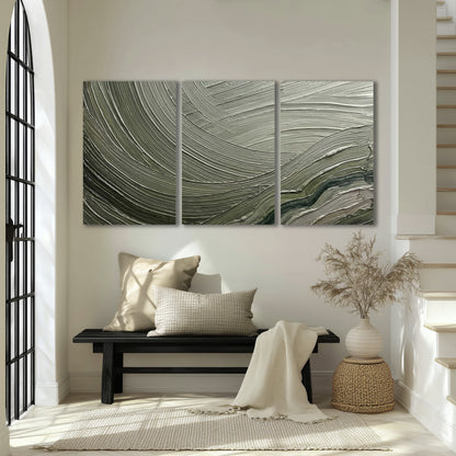 Olive and sage green abstract flowing waves with curved painted-style ridges 3 piece canvas wall art displayed in a entryway