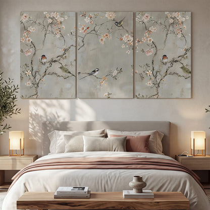 Small songbirds among pink and cream blossoms, green leaves and delicate branches on gray 3 piece canvas wall art displayed in a bedroom