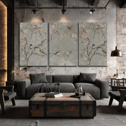 Small songbirds among pink and cream blossoms, green leaves and delicate branches on gray 3 piece canvas wall art displayed in a industrial room