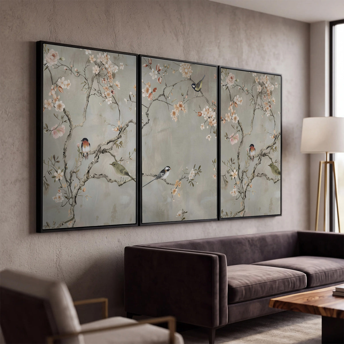 Small songbirds among pink and cream blossoms, green leaves and delicate branches on gray 3 piece framed canvas wall art displayed in a modern living room