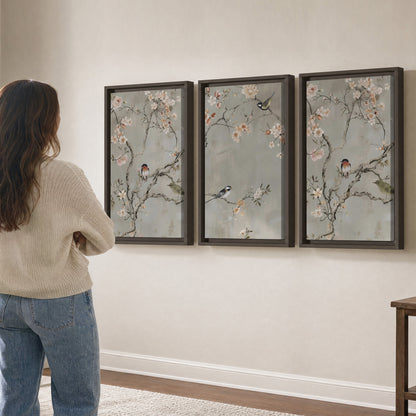 Small songbirds among pink and cream blossoms, green leaves and delicate branches on gray 3 piece framed canvas wall art three panel arrangement on a wall