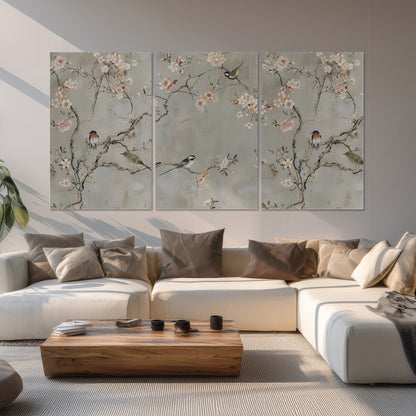 Small songbirds among pink and cream blossoms, green leaves and delicate branches on gray set of 3 poster prints displayed in a living room
