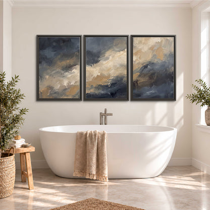 Sweeping charcoal and cream painted clouds with warm gold tones 3 piece framed canvas wall art styled in an interior
