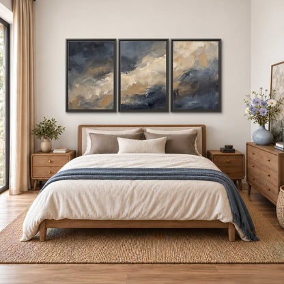 Sweeping charcoal and cream painted clouds with warm gold tones 3 piece framed canvas wall art styled in an interior