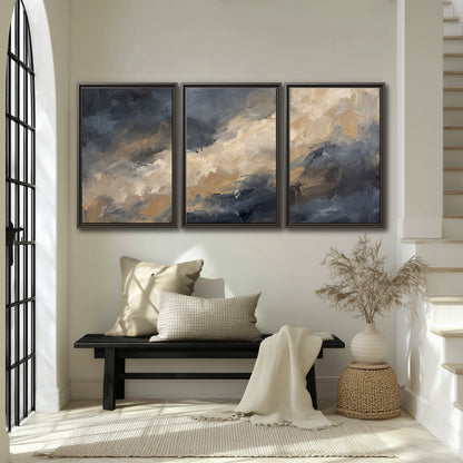 Sweeping charcoal and cream painted clouds with warm gold tones 3 piece framed canvas wall art displayed in a entryway