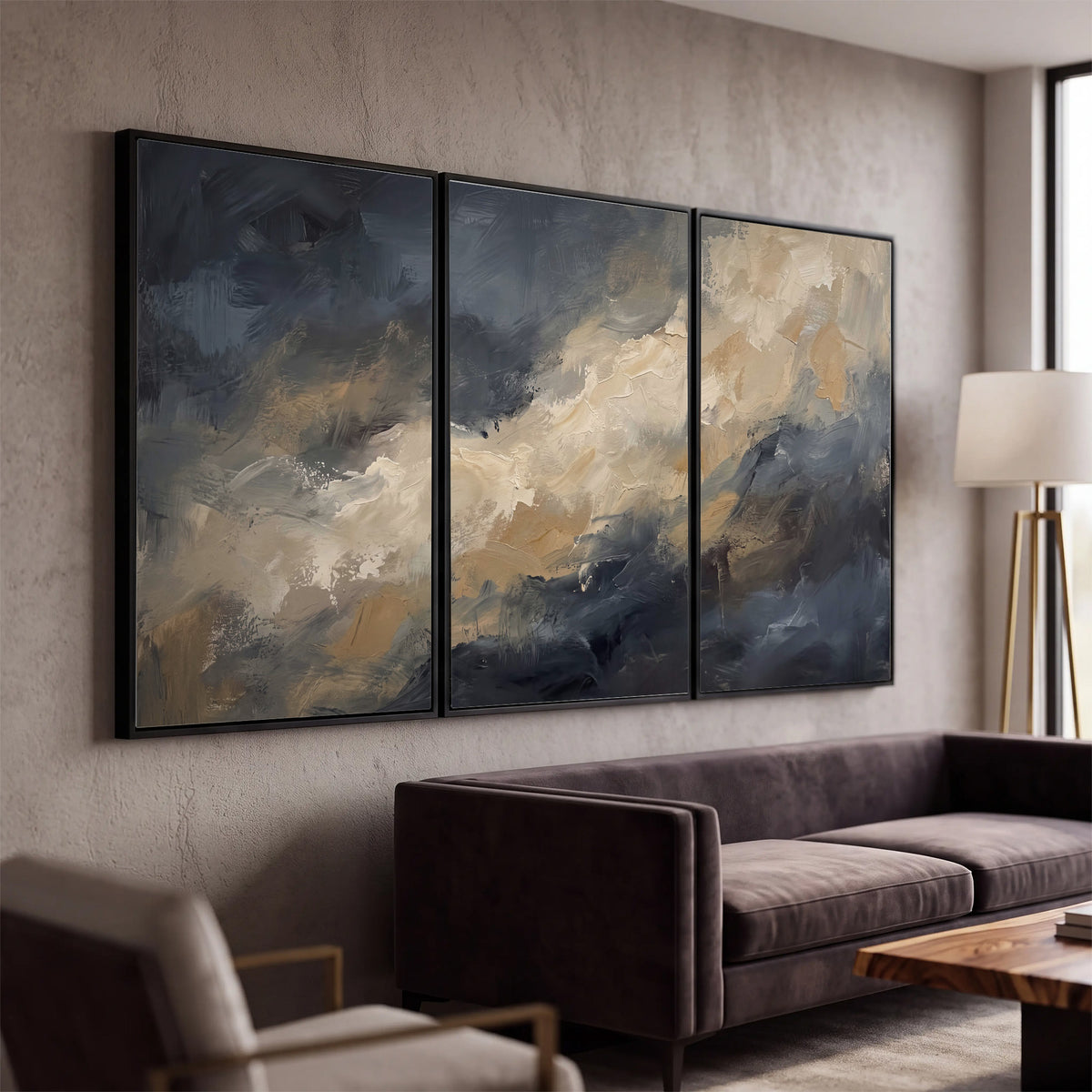Sweeping charcoal and cream painted clouds with warm gold tones 3 piece framed canvas wall art displayed in a modern living room