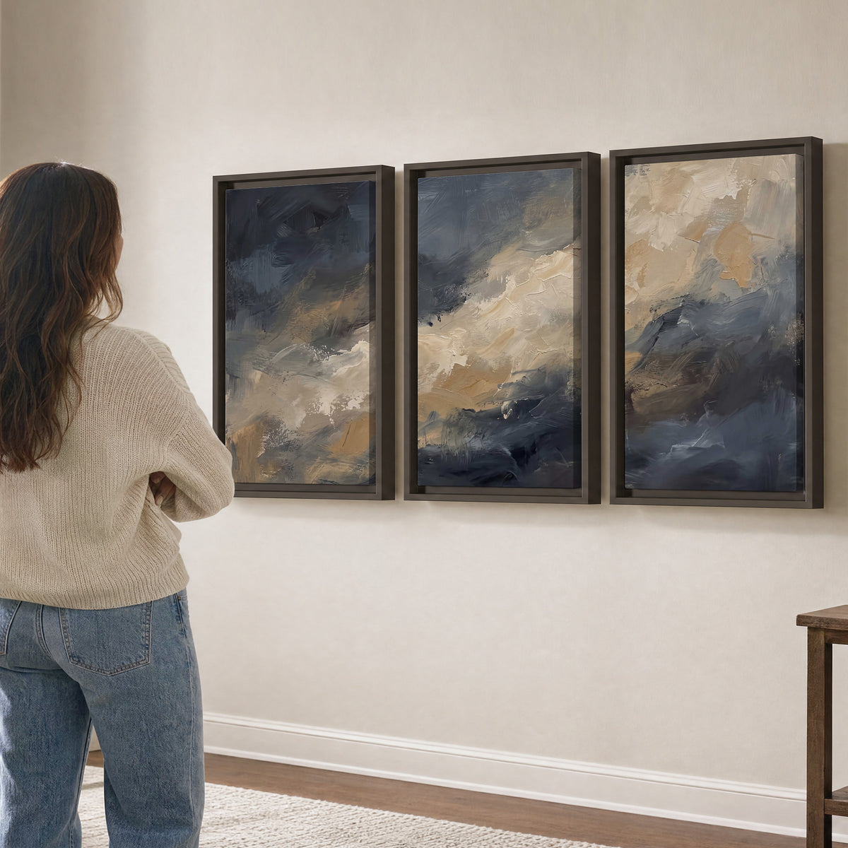 Sweeping charcoal and cream painted clouds with warm gold tones 3 piece framed canvas wall art three panel arrangement on a wall