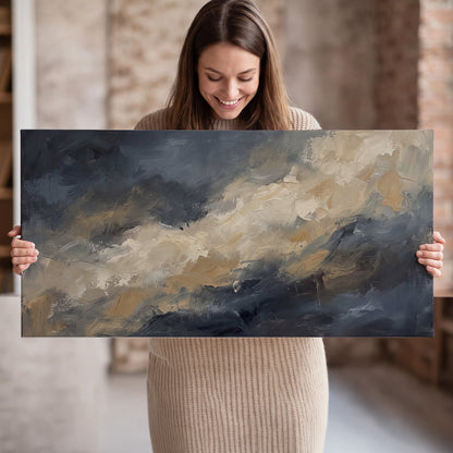 Sweeping charcoal and cream painted clouds with warm gold tones single canvas wall art held in hands