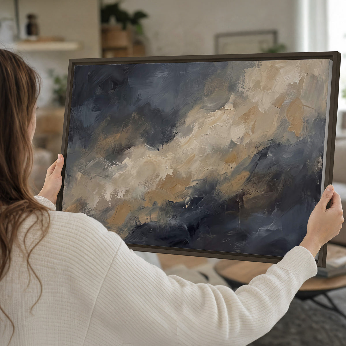 Sweeping charcoal and cream painted clouds with warm gold tones single framed canvas wall art held in hands
