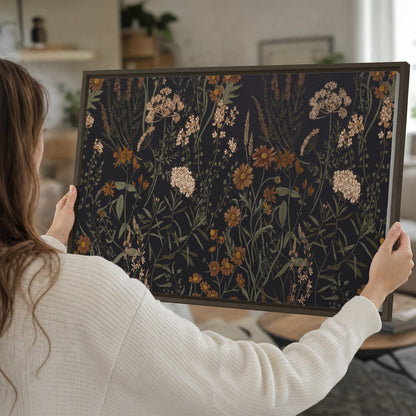 Small cream and rust flowers on a dark botanical background single framed canvas wall art held in hands