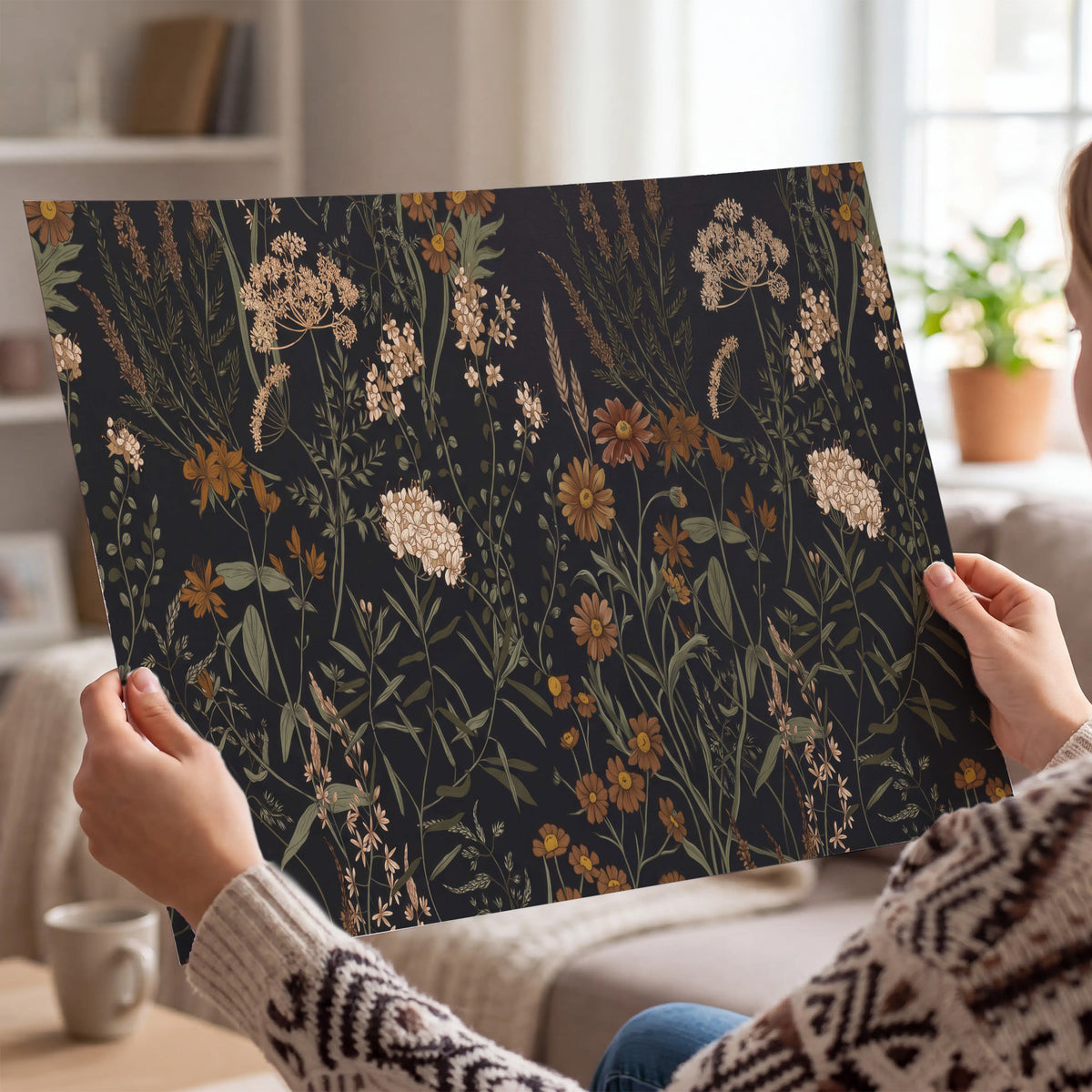 Small cream and rust flowers on a dark botanical background single poster print held in hands
