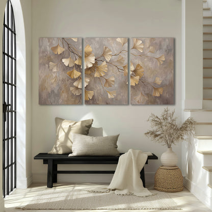 Cream and gold-colored ginkgo leaves against warm gray 3 piece canvas wall art displayed in a entryway