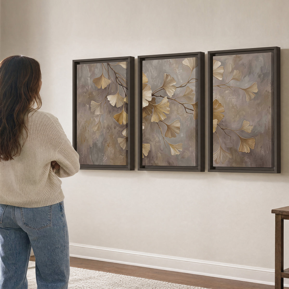 Cream and gold-colored ginkgo leaves against warm gray 3 piece framed canvas wall art three panel arrangement on a wall