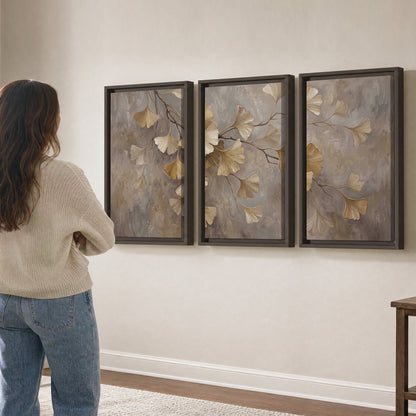 Cream and gold-colored ginkgo leaves against warm gray 3 piece framed canvas wall art three panel arrangement on a wall