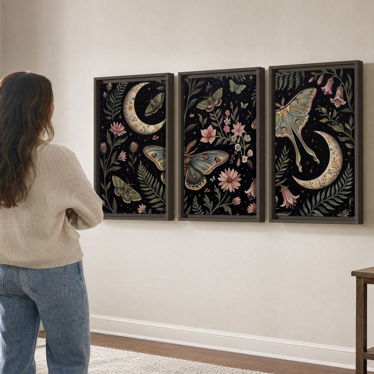 Decorative moths, crescent moons and flowers on black 3 piece framed canvas wall art three panel arrangement on a wall