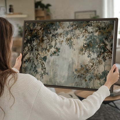Overhanging branches framing a misty woodland clearing single framed canvas wall art held in hands