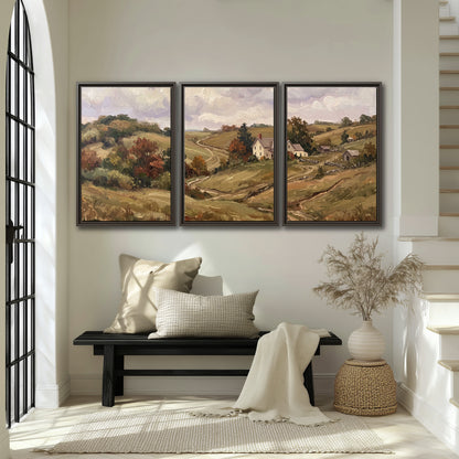 Warm rolling fields and countryside cottages beneath soft clouds 3 piece framed canvas wall art displayed in a entryway