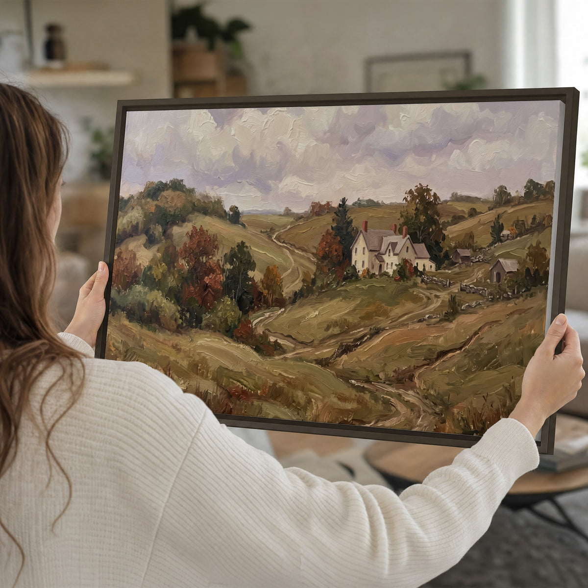 Warm rolling fields and countryside cottages beneath soft clouds single framed canvas wall art held in hands
