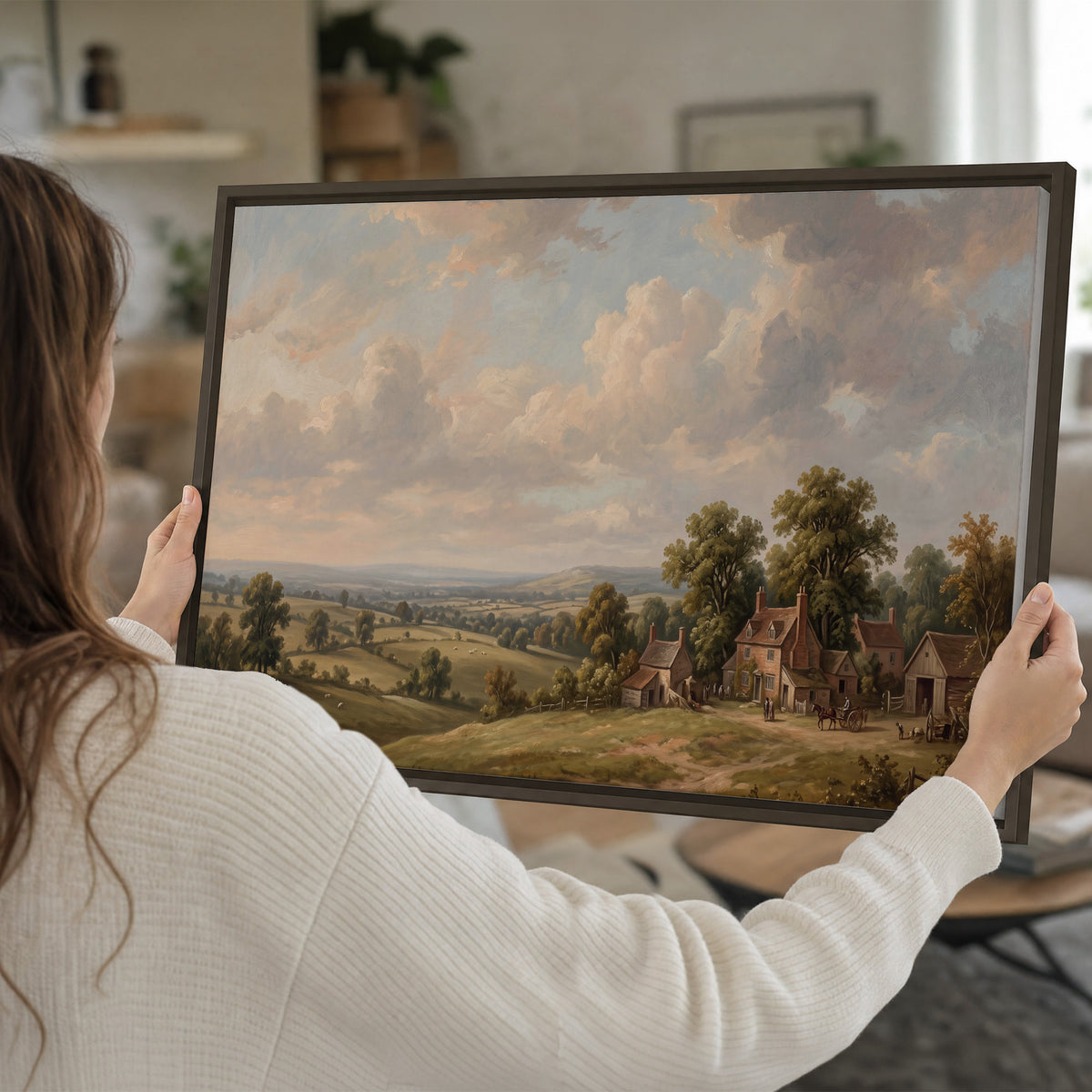 Small cottages overlooking fields beneath a luminous cloudy sky single framed canvas wall art held in hands