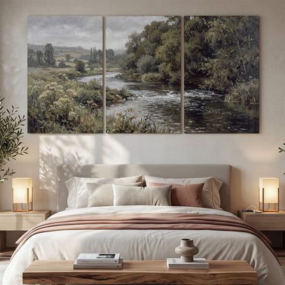 A gently flowing river bordered by olive-green trees and flowers 3 piece canvas wall art displayed in a bedroom