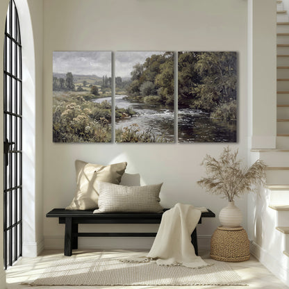 A gently flowing river bordered by olive-green trees and flowers 3 piece canvas wall art displayed in a entryway