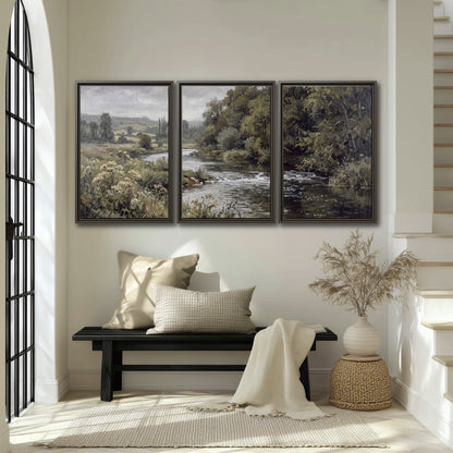 A gently flowing river bordered by olive-green trees and flowers 3 piece framed canvas wall art displayed in a entryway
