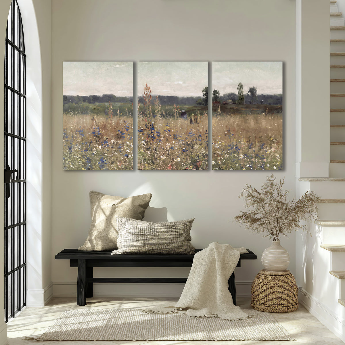 A loose painterly meadow with scattered blue and white wildflowers 3 piece canvas wall art displayed in a entryway