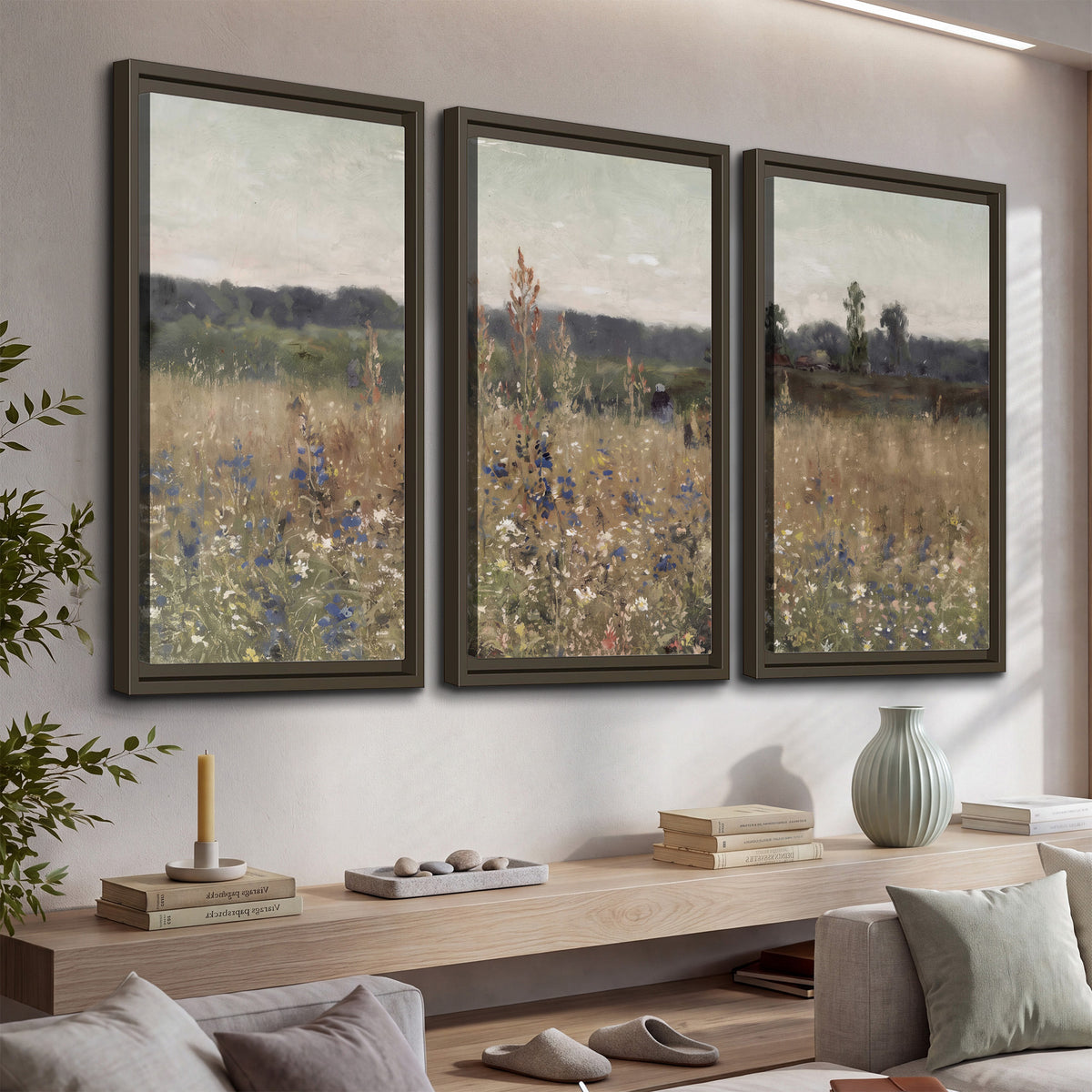 A loose painterly meadow with scattered blue and white wildflowers 3 piece framed canvas wall art displayed in a console