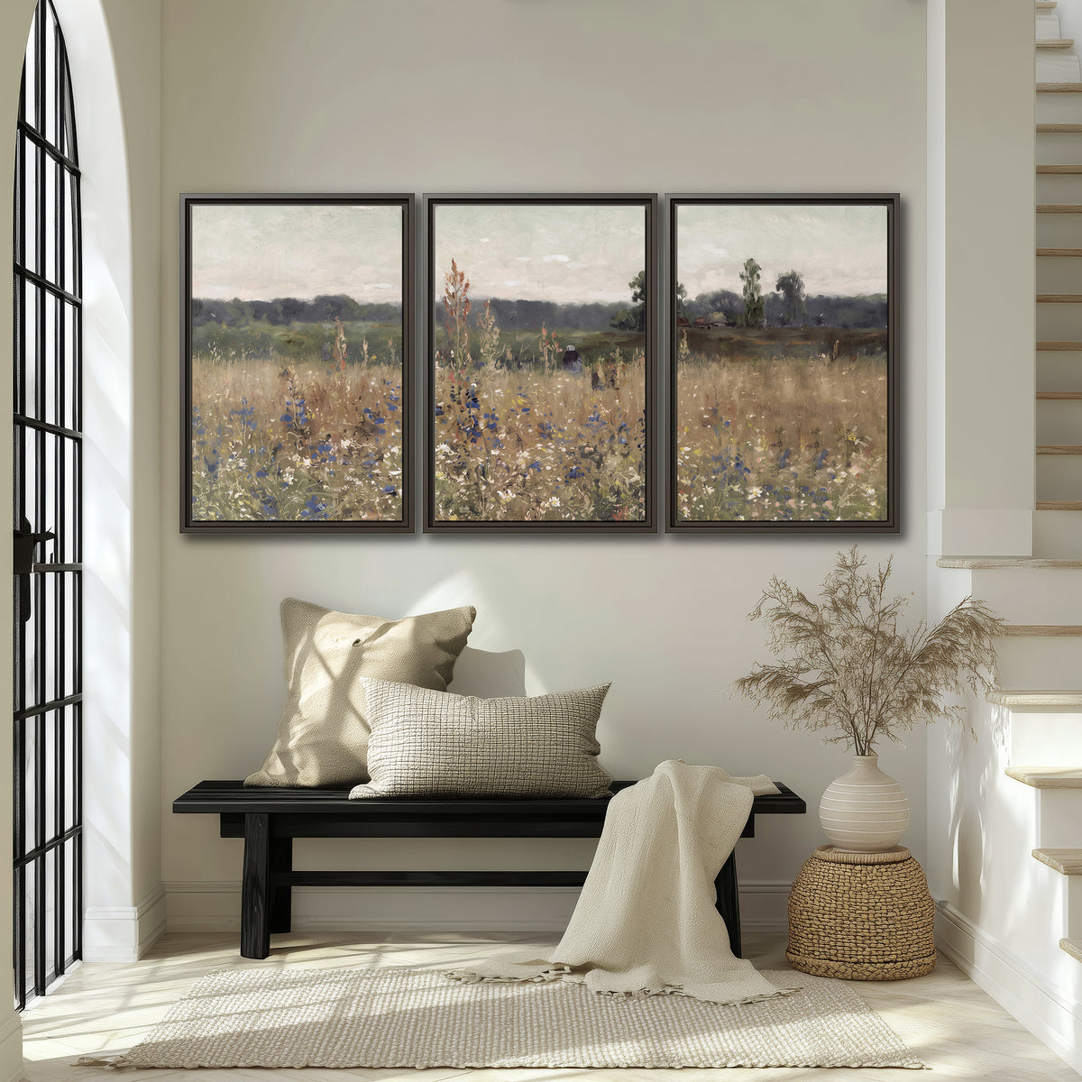 A loose painterly meadow with scattered blue and white wildflowers 3 piece framed canvas wall art displayed in a entryway